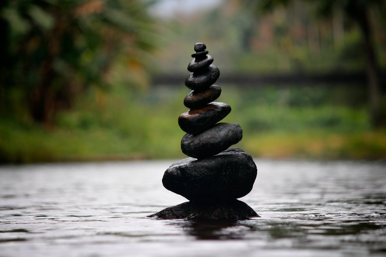 Balanced stones in a serene river evoke a sense of peace and tranquility.